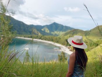 Rear view of woman standing by lake against sky