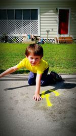 Portrait of smiling playful boy on footpath outside house