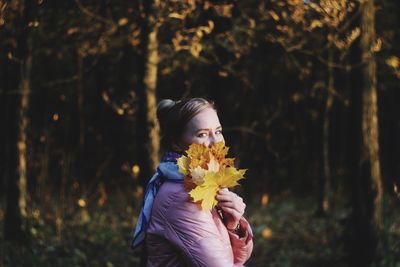 Portrait of woman holding flowering plant