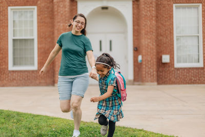 Young millennial mother sending daughter off back to school