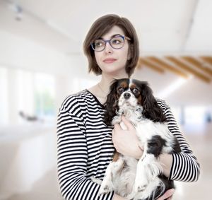 Woman holding dog while standing at home