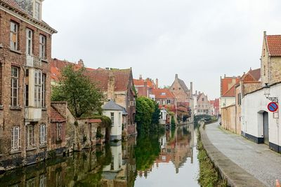 Canal amidst city against sky