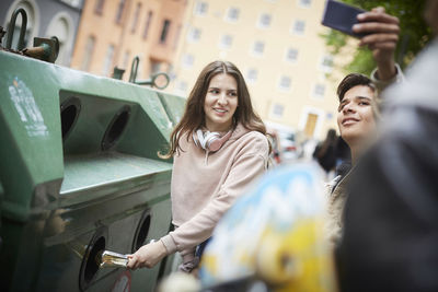 Portrait of smiling young woman photographing in city