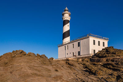 Low angle view of lighthouse against clear blue sky, menorca, spain