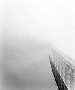 Low angle view of suspension bridge in foggy weather