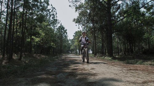 Man riding bicycle on road in forest