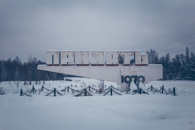 Built structure on snow covered field against sky