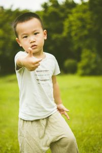 Portrait of boy gesturing thumbs up while standing on field