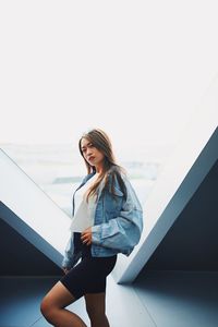 Portrait of young woman standing against wall