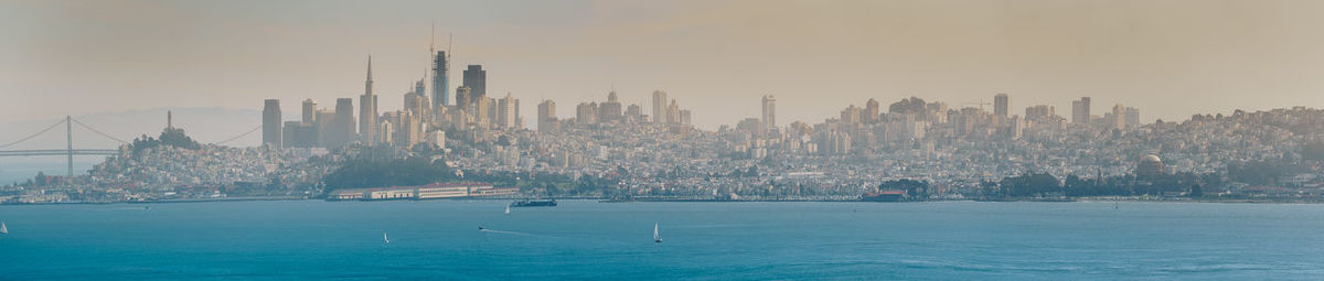 Panoramic view of bay against modern buildings in city