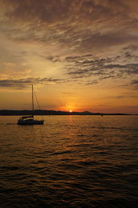Silhouette sailboats in sea against sky during sunset