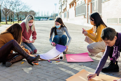 Females drawing on poster outdoors