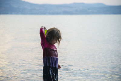 Rear view of woman standing by sea