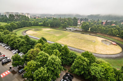 High angle view of golf course in city against sky