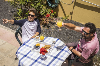 High angle view of cheerful father and son gesturing while having food and drink at table