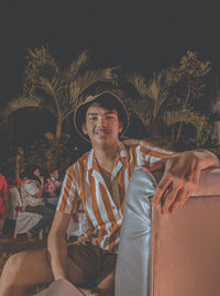 Portrait of a smiling young man sitting against wall