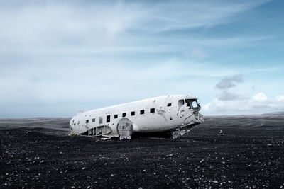 Abandoned airplane on land against sky