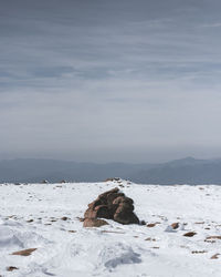 Rocks on snow covered land against sky