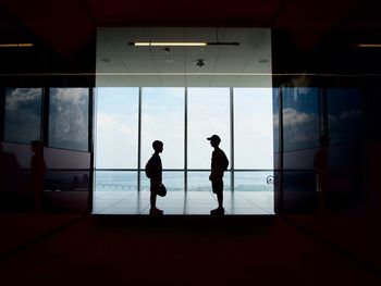 Rear view of silhouette people standing at airport