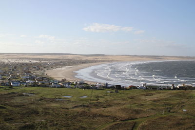 Scenic view of field by sea against sky