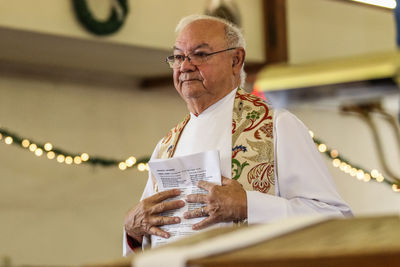 Senior man with paper standing in building