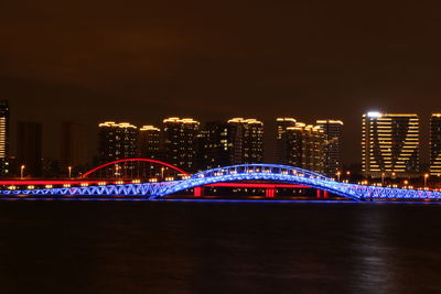 Light trails on bridge in city against sky at night