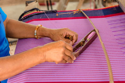 Midsection of woman working on loom in factory