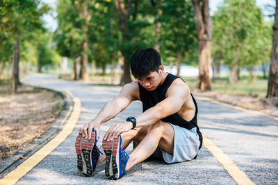 Man sitting on road against trees