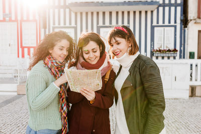 Tourist female friends reading a map in in front of colorful houses.costa nova, aveiro, portugal