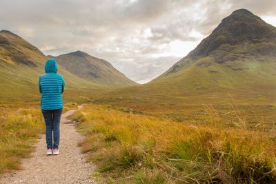 Rear view of woman standing on mountain against sky