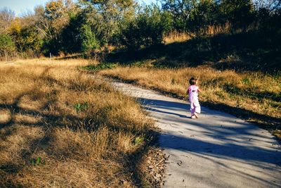 Rear view of girl walking on footpath in forest