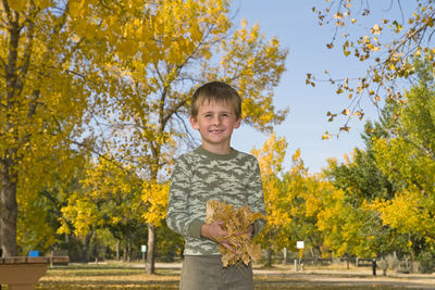 Portrait of smiling boy standing against trees
