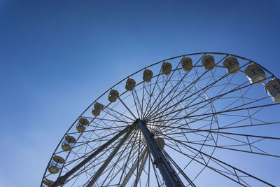 Low angle view of ferris wheel against clear blue sky