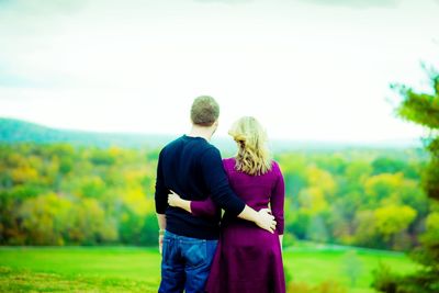 Rear view of couple on grass against sky