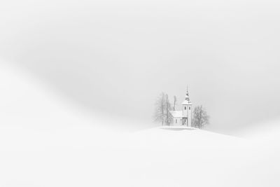 Church on snow covered field against clear sky