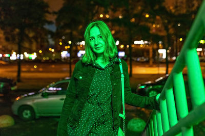 Portrait of a young woman in a night city in neon green on a summer evening. city lights.