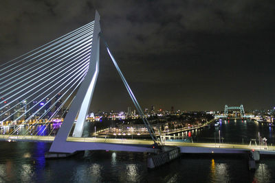 Illuminated bridge over river against sky at night