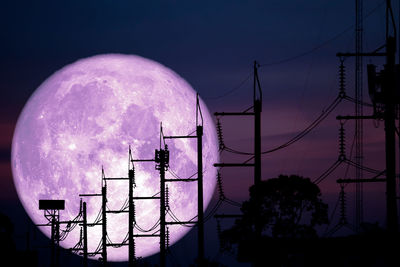 Low angle view of electricity pylon against sky at night