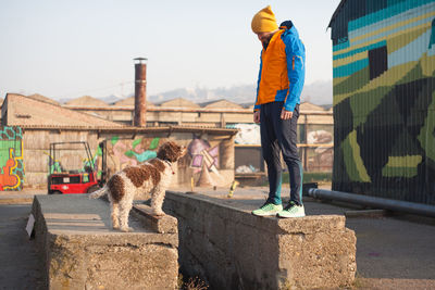 Man standing by dog on retaining wall