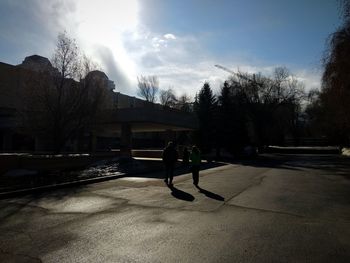Silhouette man on sidewalk against sky in city