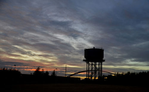 Water tower against sky at sunset
