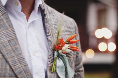 Midsection of man wearing flowers and suit during event