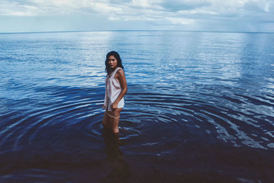 Woman standing in sea against sky