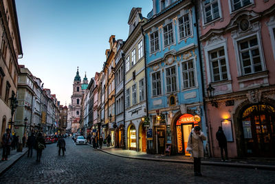 People walking on street amidst buildings in city