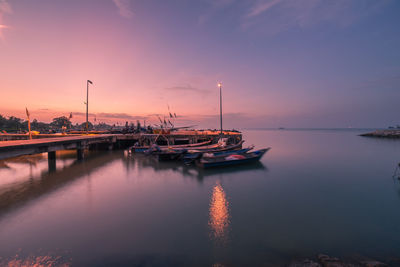 Sailboats moored in marina at sunset