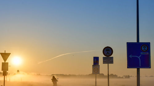 Road sign against clear sky during sunset