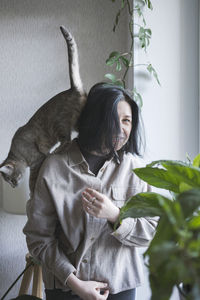 A young woman holds a gray cat with yellow eyes in her arms. the cat and her mistress at home. 