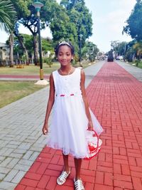 Portrait of smiling woman standing on footpath