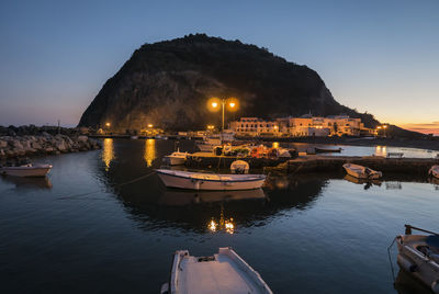 Boats moored on sea against sky at dusk