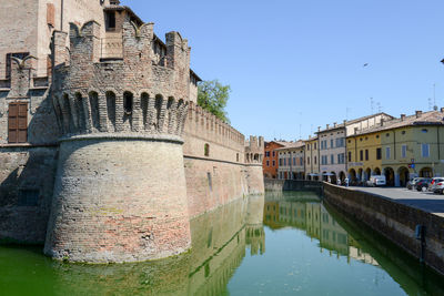 Reflection of building in canal against clear sky